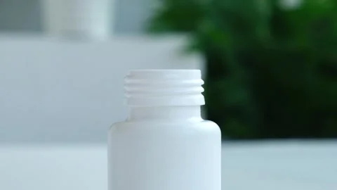 Pills falling into bottle closeup, slow motion, Green plant on background Stock-Footage 344839043