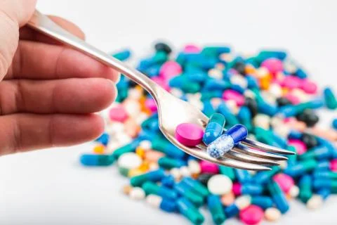 Pills on a fork. Tablets and pils. Scattered pills. Stock Photos