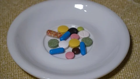 Pills. Medication closeup. A pile of multi-colored tablets lies on a white Stock Footage 99440370