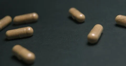 Pills medicine falling on black background close-up slow motion, studio shot in Stock Footage 126369461
