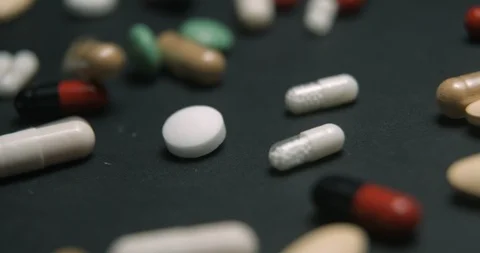 Pills medicine falling on black background close-up slow motion, studio shot in Video stock 126369791