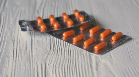 The pills in orange capsules fall on a white table Stock Footage 62767104