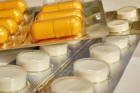 Pills in a package lying on a white table Stock Photos