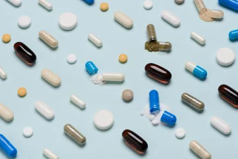 Pills pattern with some medicine capsules open and drug content spilled Stock Photos