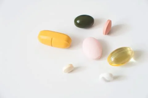 Pills in a row, various forms, white background. Multi-colored pills close-up an Stock Photos