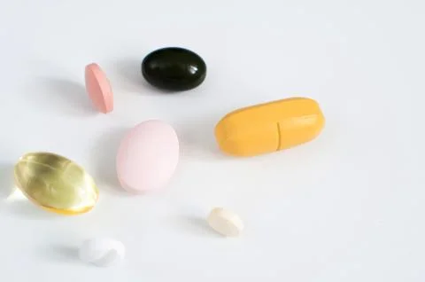 Pills in a row, various forms, white background. Multi-colored pills close-up an Stock Photos