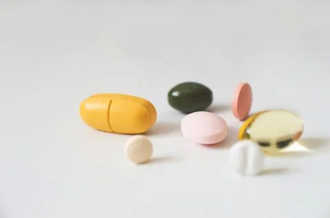 Pills in a row, various forms, white background. Multi-colored pills close-up an Stock Photos