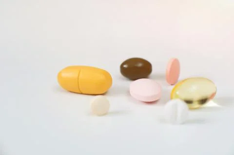 Pills in a row, various forms, white background. Multi-colored pills close-up an Stock Photos