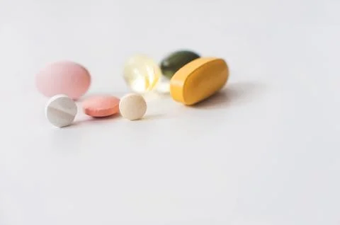 Pills in a row, various forms, white background. Multi-colored pills close-up an Stock Photos