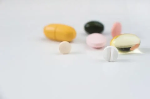 Pills in a row, various forms, white background. Multi-colored pills close-up an Stock Photos