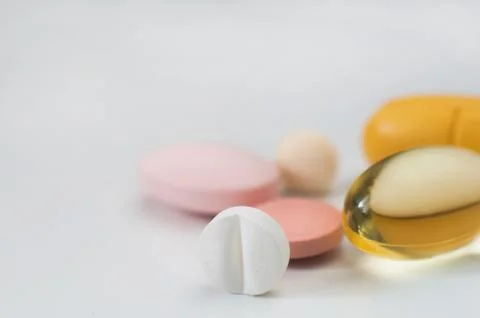 Pills in a row, various forms, white background. Multi-colored pills close-up an Stock Photos
