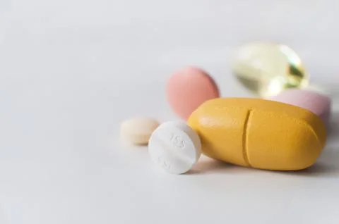 Pills in a row, various forms, white background. Multi-colored pills close-up an Stock Photos