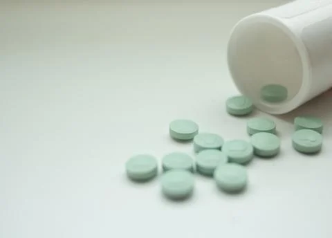 Pills spill out of container Stock Photos