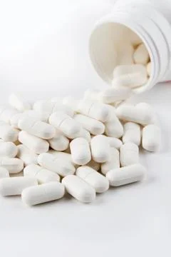 Pills spilling from plastic container Stock Photos