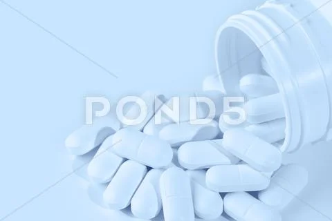 Pills spilling from plastic container Stock Photos