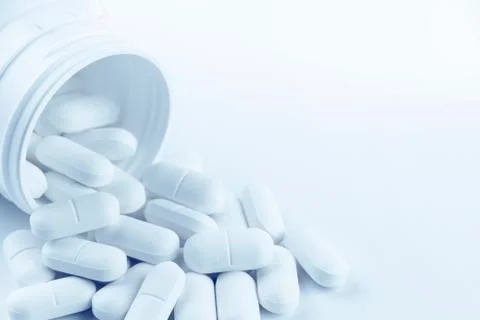 Pills spilling from plastic container Stock Photos