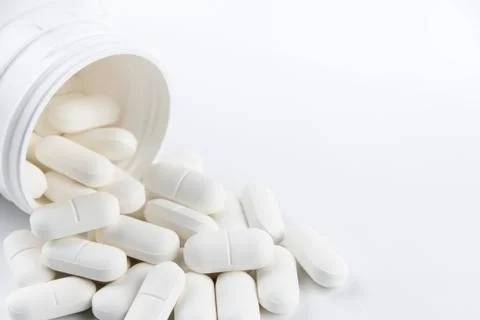Pills spilling from plastic container Stock Photos