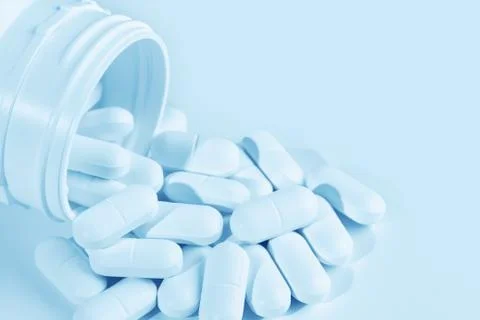 Pills spilling from plastic container Stock Photos