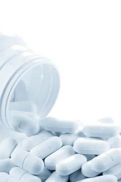 Pills spilling from plastic container Stock Photos
