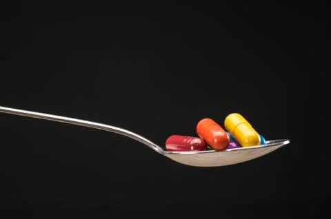 Pills in spoon Stock Photos