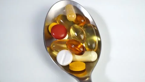 Pills on a spoon on white background Stock Footage 276643204