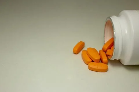 Pills spread over a white table, next to the open bottle Foto stock