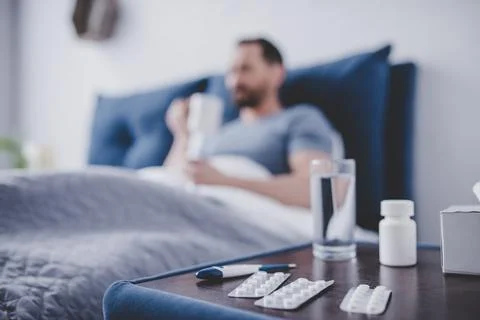 Pills on table with sick man in the bed Stock Photos