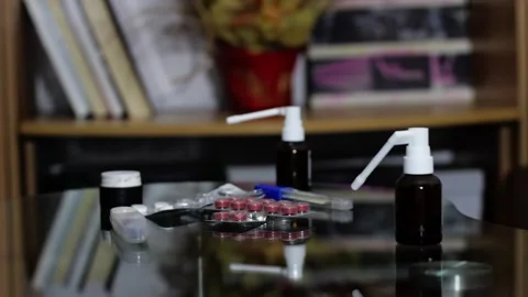 Pills, two thermometers and two throat sprays on the table in the house Stock Footage 258796403