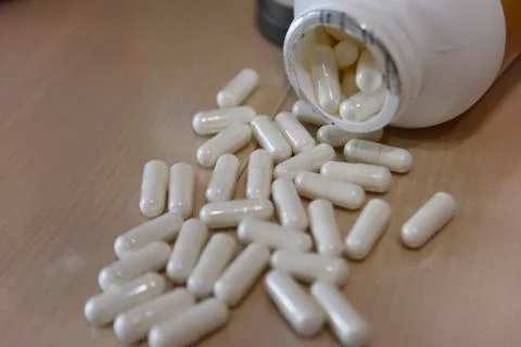 Pills in the white plastic bottle on the table Stock Photos