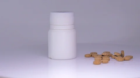Pills on the white table with white bottle on a white background Stock Footage 129607137