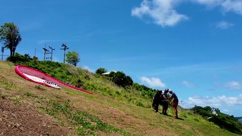 The pilot and paraglide instructor prepare the passenger for the flight Stock Footage 173721699