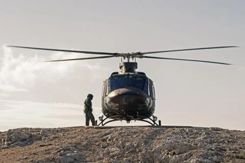 Pilot checking helicopter before takeoff from helipad on top of mountain Stock Photos