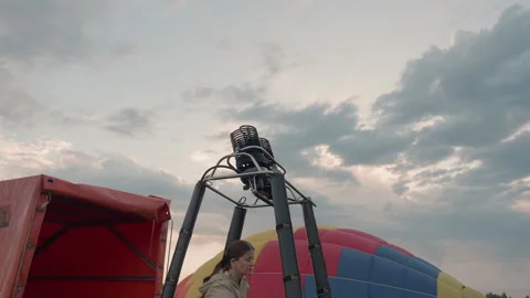 Pilot controls burner flame under hot air balloon basket at dusk Stock Footage 317193671