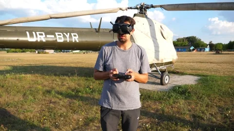Pilot of drone wearing goggles, operating remote control for helicopter Stock Footage 318872710