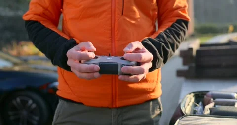 Pilot hands operating DJI drone remote controller outdoors Stock Footage 341923398