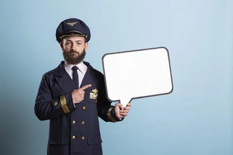 Pilot holds blank speech bubble sign against blue studio background Stock Photos