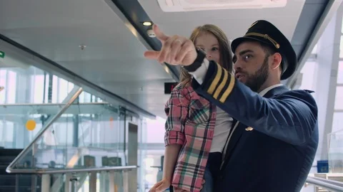 Pilot hugging little smiling daughter, showing her smth with finger in airport Stock Footage 109146853