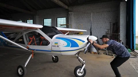 Pilot inspecting aircraft engine in hangar, demonstrating meticulous attention 스톡 동영상 347871554