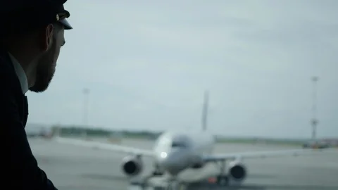 Pilot looking throuhg the airport window at airfield, Pig white plane on Stock Footage 109286239