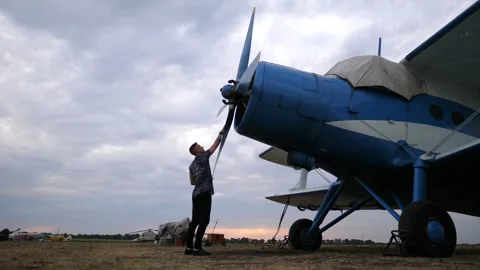Pilot preparing aircraft for flight, walking towards blue propeller plane Видео 347871835