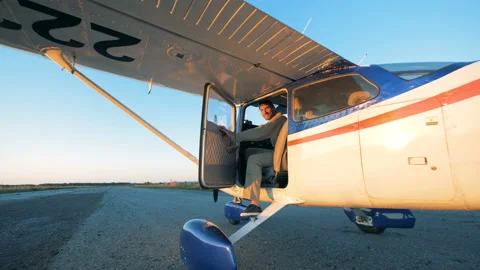 A pilot is sitting in cropduster's cockpit, winking and closing the door Stock Footage 96854428