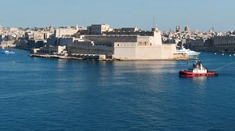 Pilot tag boat pulling cargo ship with with nice Valletta fortress view Stock Footage 63899147