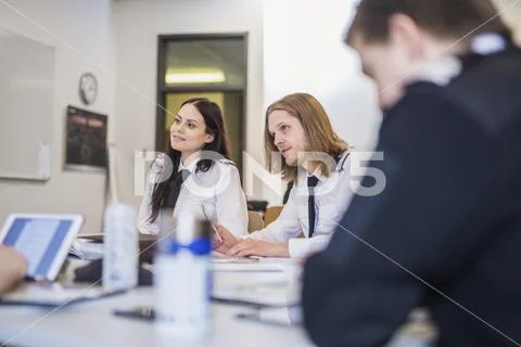 Pilot trainees looking away while sitting at desk in classroom Stock Photos