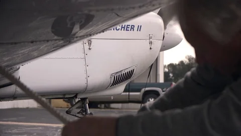 Pilot Tying Ropes to Secure Small Airplane Stock Footage 99268408