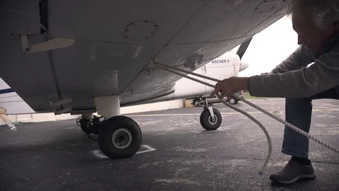 Pilot Tying Ropes to Secure Small Airplane Stock Footage 99268451