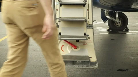 Pilot walking up airplane steps, entering jet and closing hatch Stock Footage 61492795