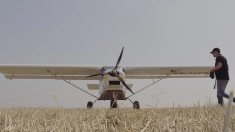 Pilot walking to his plane in a field Stock Footage 275384811
