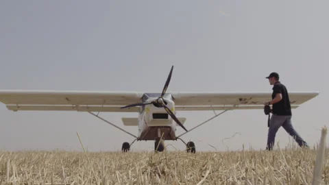Pilot walking to his plane in a field Stock Footage 275397467