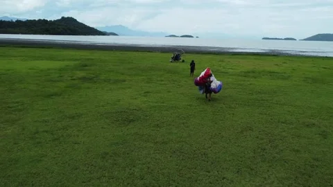 Pilot walking with paraglider after end flight on the Jabaquara Beach in Paraty Stock Footage 328349608