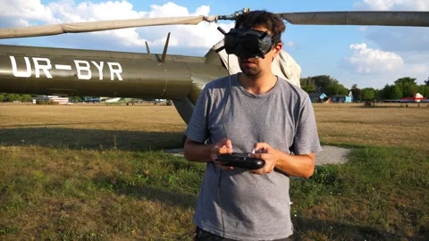 Pilot wearing goggles, operating remote control for helicopter Video stock 321770614